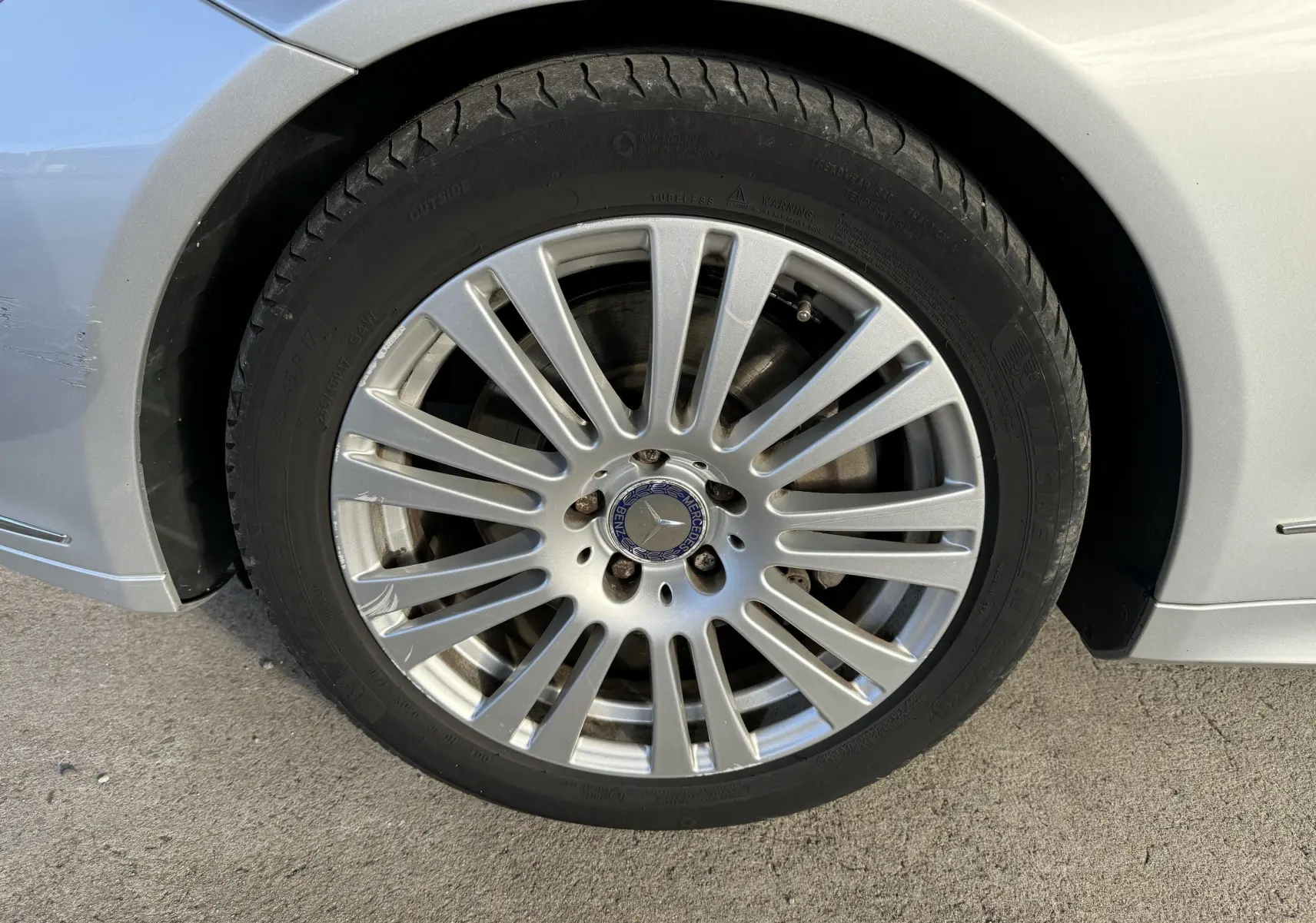 Gros plan sur la jante alliage argentée avec logo Mercedes d'une Mercedes Classe E 250 Coupé gris côté arrière droit.