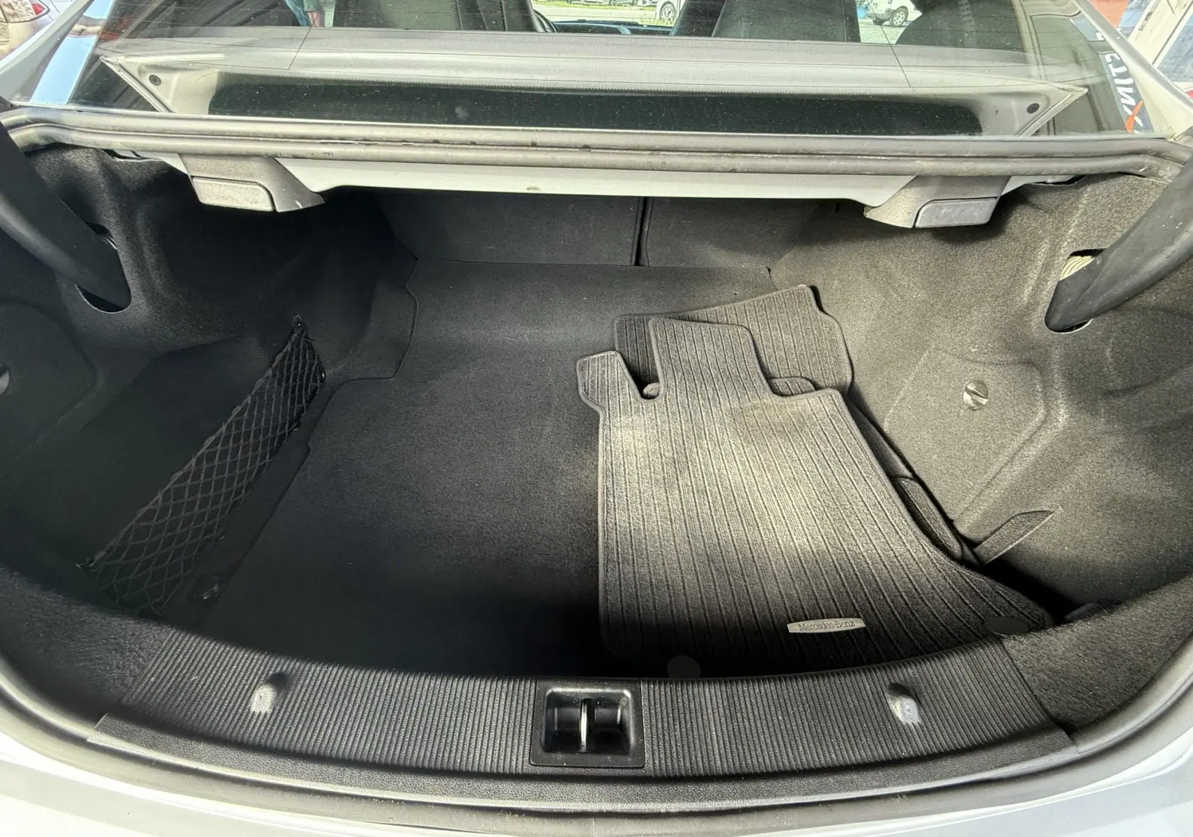 Coffre ouvert d'une Mercedes Classe E 250 Coupe gris, montrant un tapis de sol intérieur gris foncé.