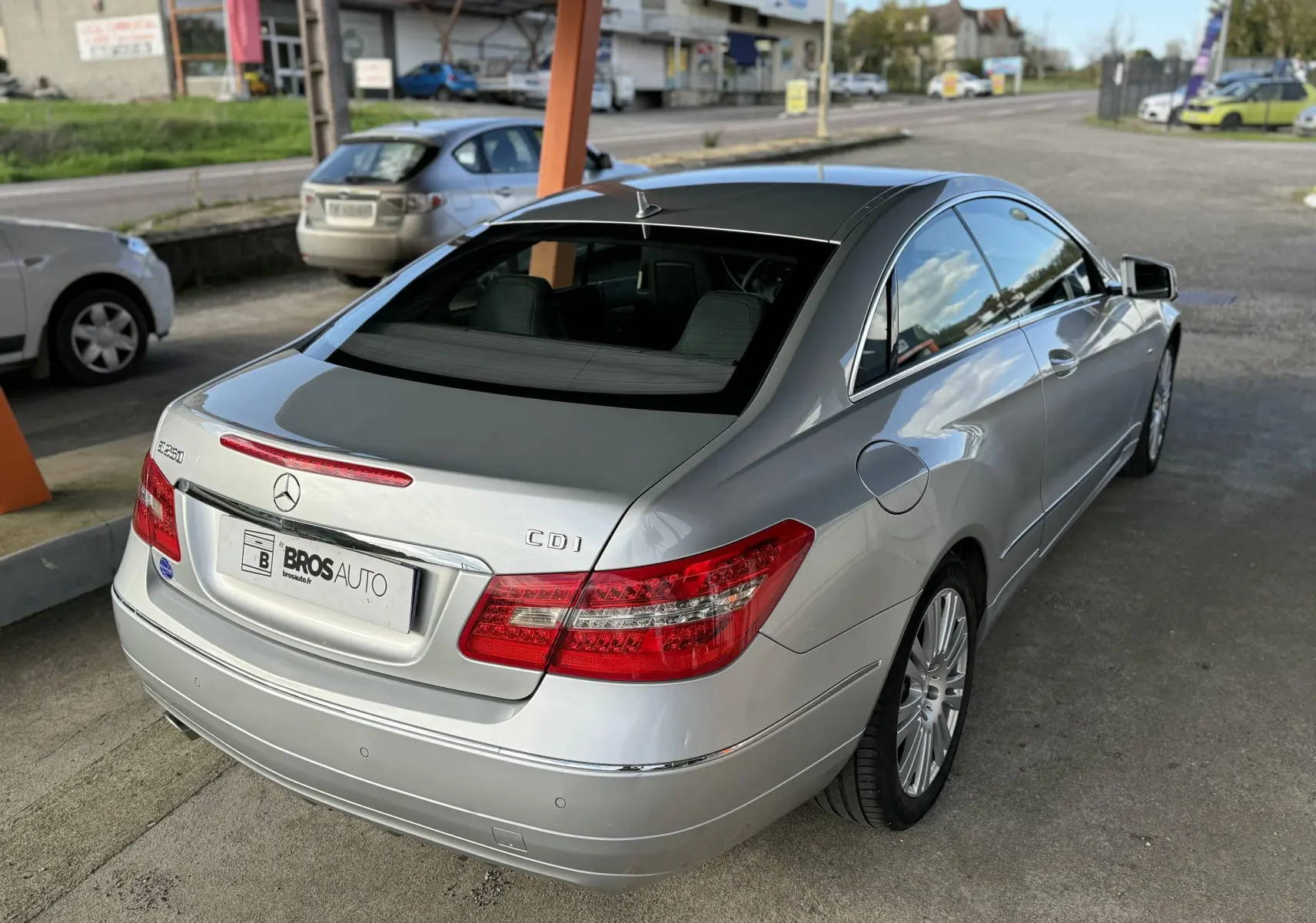 Vue 3/4 arrière droite d'une Mercedes Classe E 250 CDI gris métallisé stationnée sous abri avec jantes alliage.