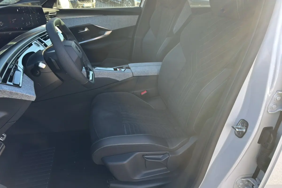 Intérieur du Peugeot 3008 Hybrid 2024 vu côté conducteur, sièges noirs avec surpiqûres et détails gris clair.