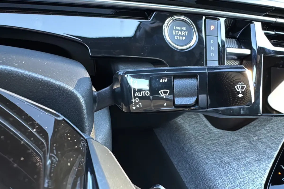 Gros plan sur la commande d'essuie-glace et le bouton start/stop du Peugeot 3008 Hybrid blanc okénite, intérieur moderne.