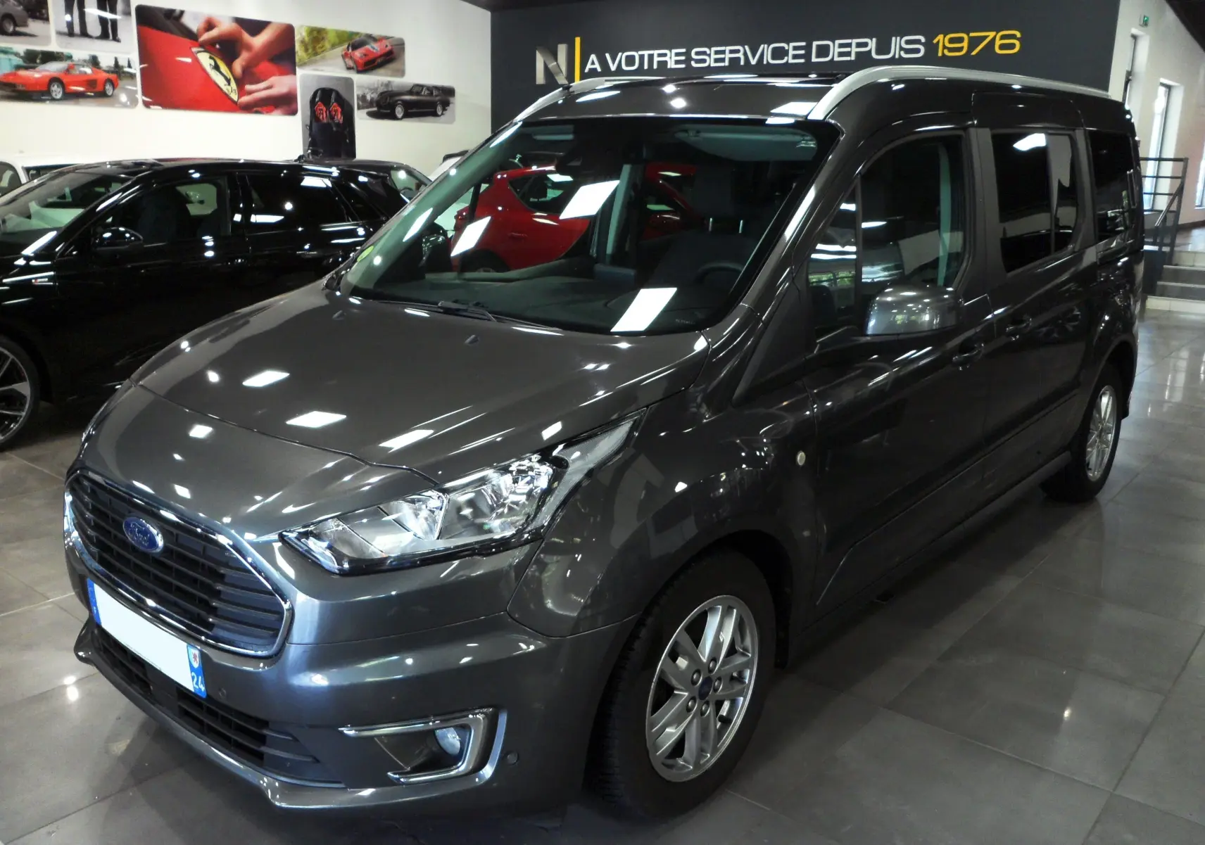 Vue 3/4 avant d'un Ford Grand Tourneo Connect gris Magnetic 2020 en showroom avec jantes alliage et vitres teintées.