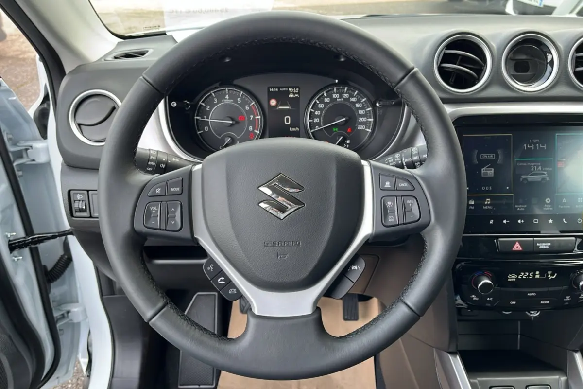 Vue intérieure centrée sur le volant du Suzuki Vitara 2025 blanc nacré avec tableau de bord et écran tactile.