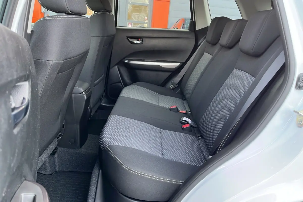 Vue côté droit de l'habitacle arrière du Suzuki Vitara 2025 blanc nacré, sièges tissu bicolore gris et noir.