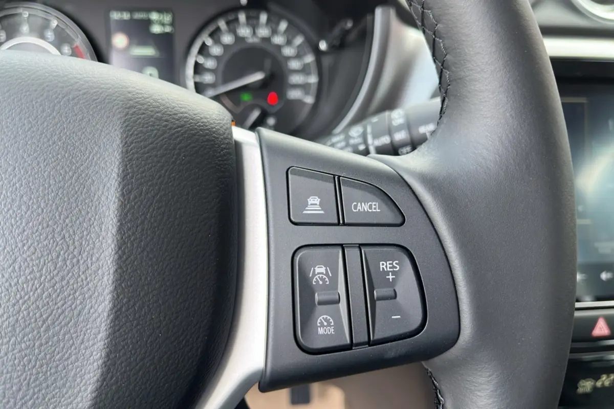 Gros plan sur les commandes au volant du Suzuki Vitara 2025 blanc nacré, avec régulateur de vitesse et fonction cancel.