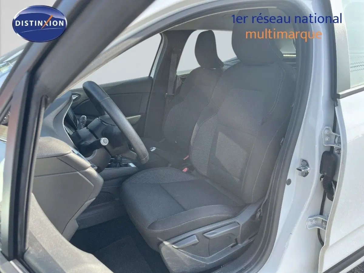 Vue côté gauche intérieur de la Renault Clio blanche 2020 montrant les sièges avant en tissu noir et le volant multi-fonctions.