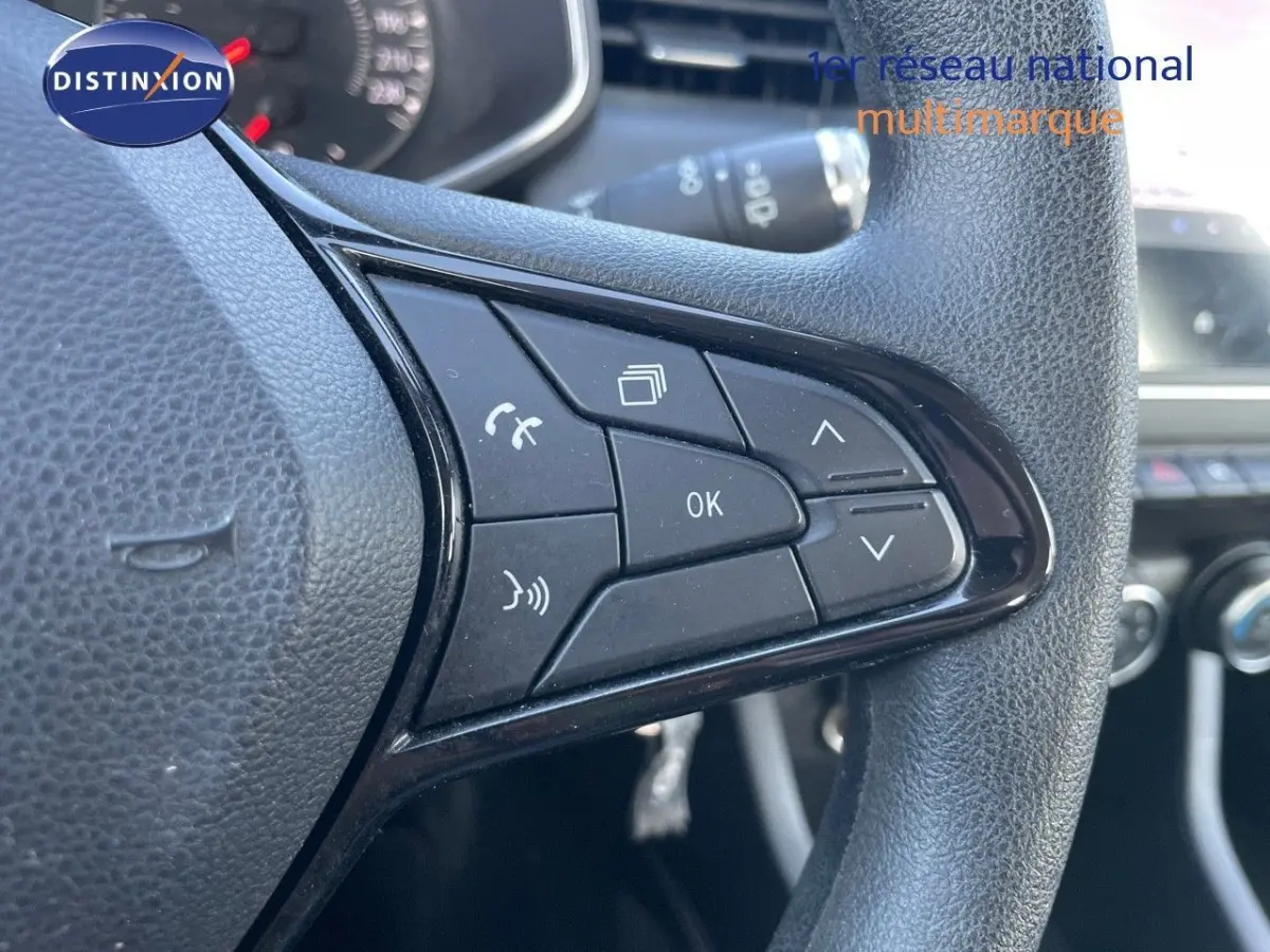 Gros plan sur les commandes multifonctions noires du volant d'une Renault Clio blanche, version Air Nav Blue dCi 85 Ch Société.