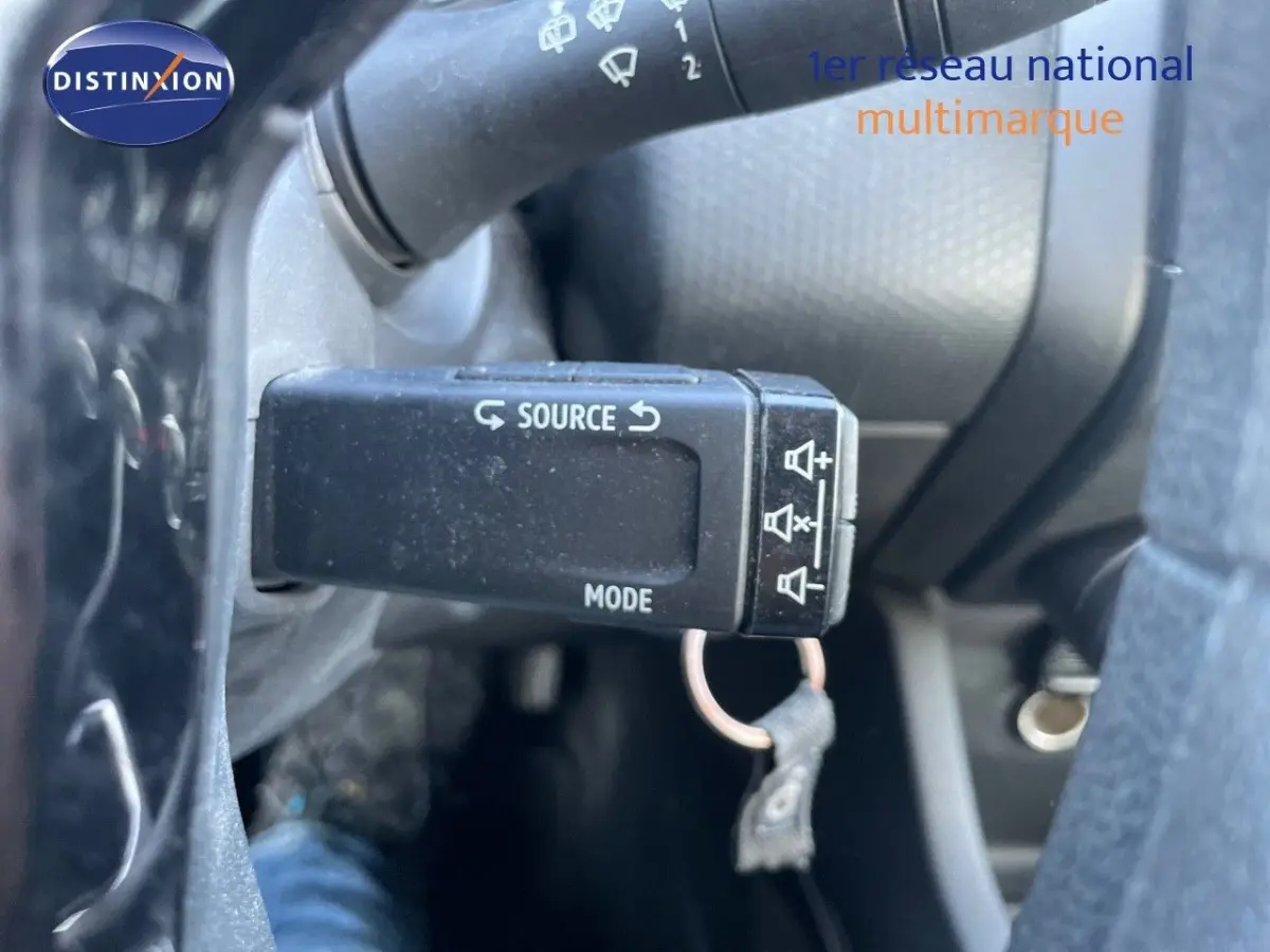 Gros plan sur la commande au volant de la Renault Clio blanche, avec bouton source et mode visible.