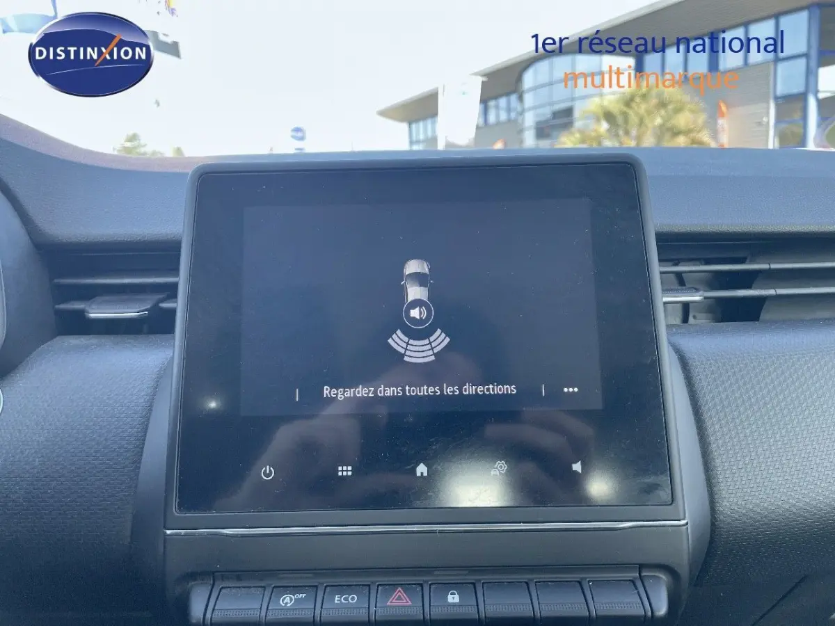 Écran tactile central allumé dans l'habitacle d'une Renault Clio blanche, vue de face du tableau de bord.
