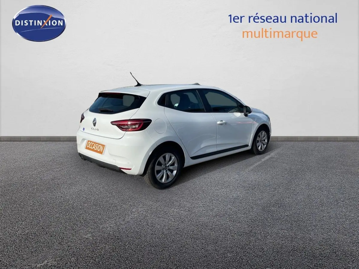 Renault Clio blanche vue 3/4 arrière côté droit, stationnée devant un mur blanc avec logo Distinxion.