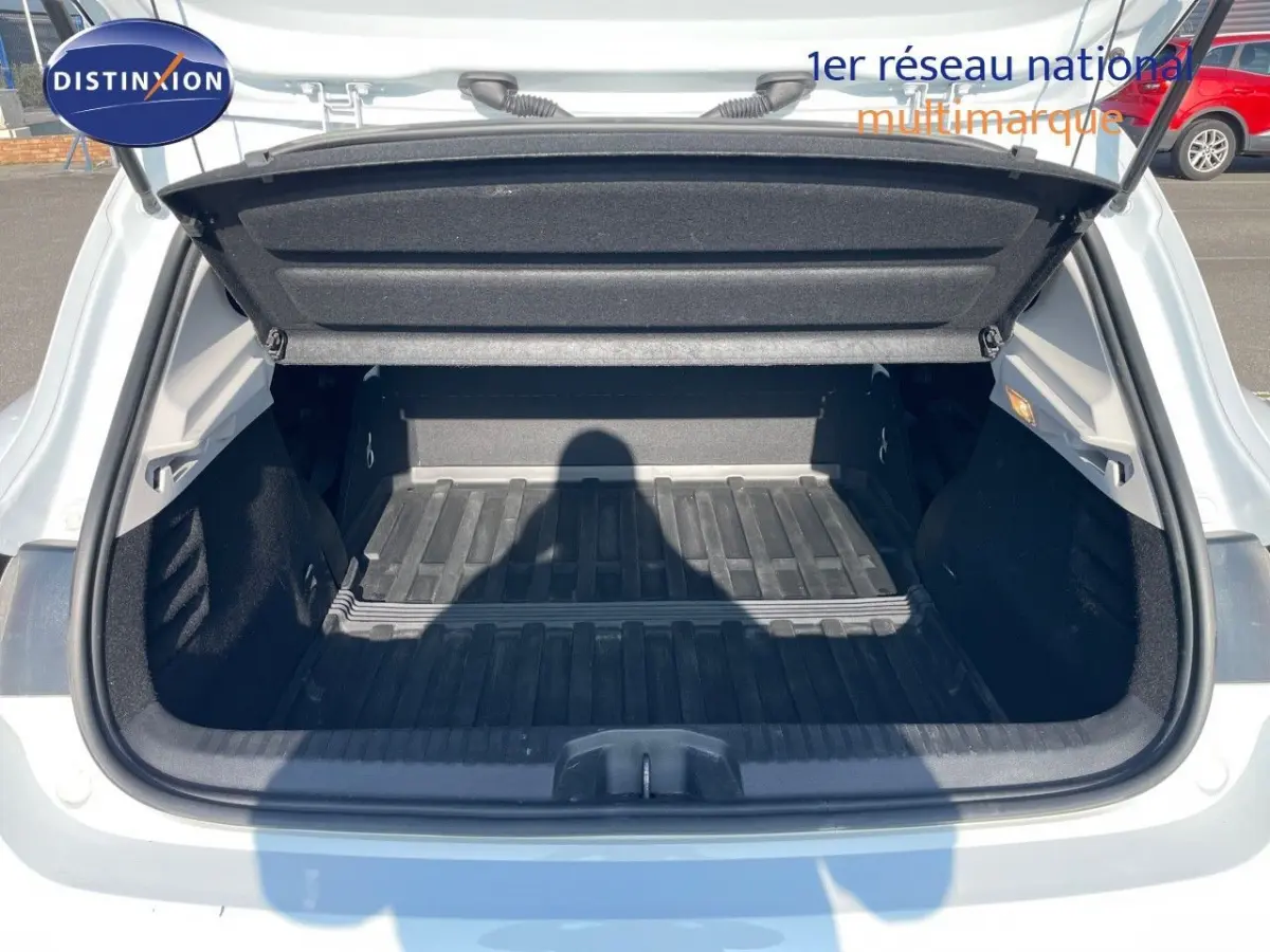 Coffre ouvert d'une Renault Clio blanche vue de l'arrière, montrant un espace de chargement vide et propre.