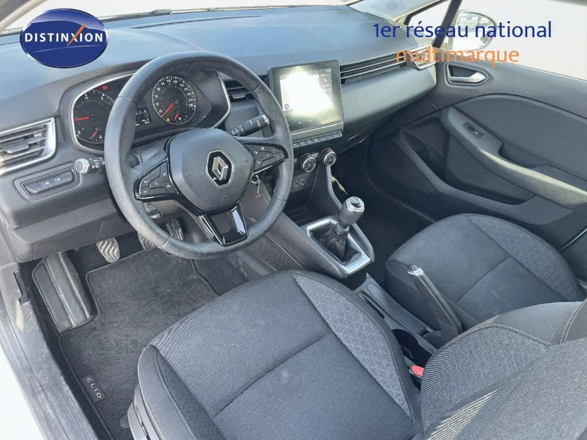 Vue intérieure côté conducteur de la Renault Clio blanche 2020, tableau de bord avec écran tactile et volant multifonctions.