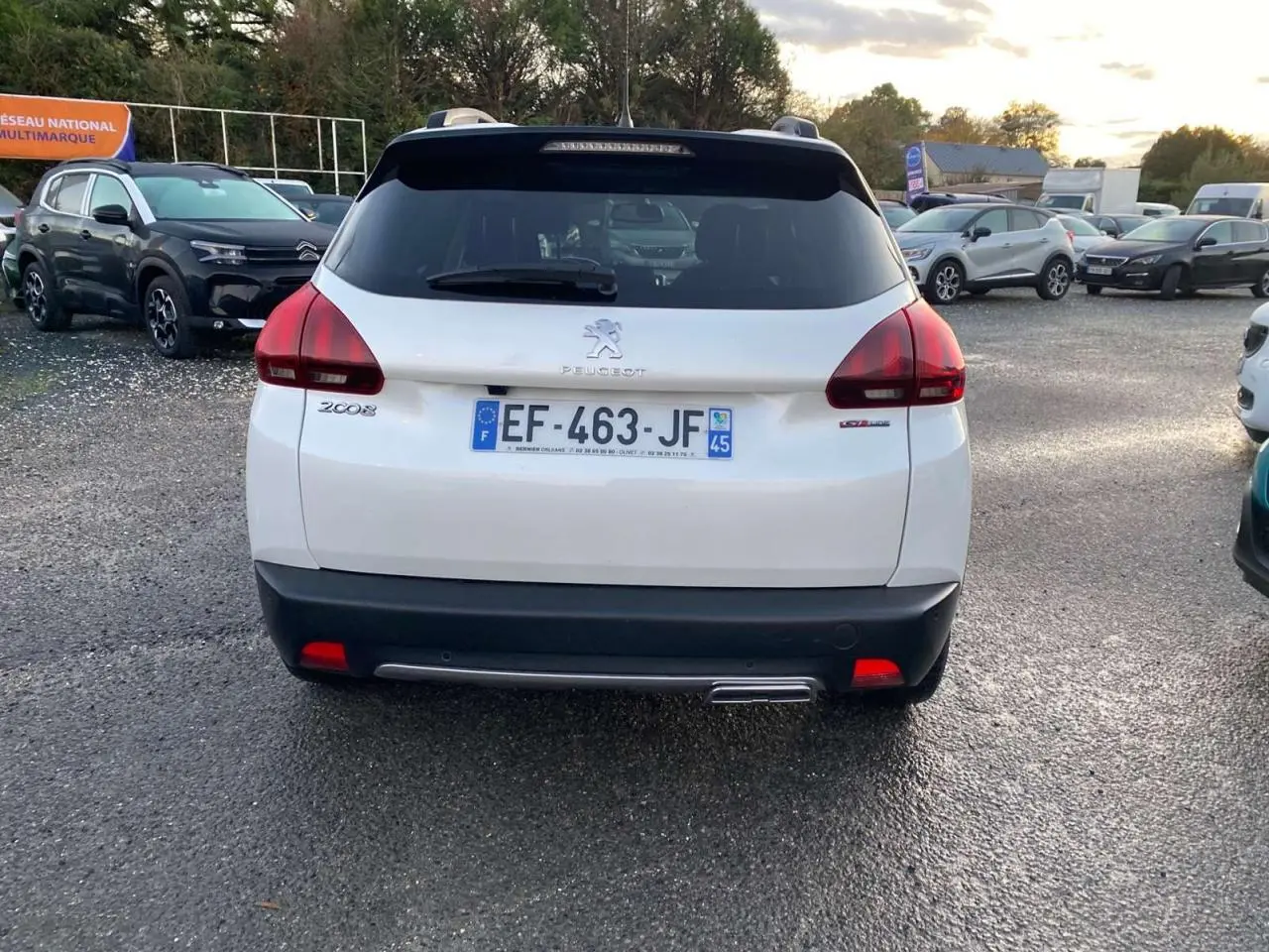 Vue arrière d'un Peugeot 2008 blanc GT Line de 2016 avec plaque d'immatriculation française visible sur un parking.