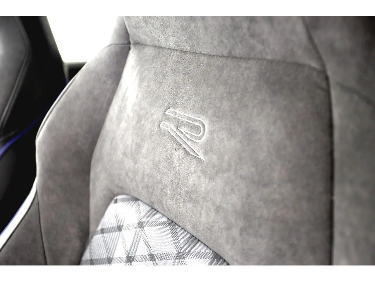 Gros plan sur le siège avant gris avec logo R brodé et motif écossais à l'intérieur d'une Volkswagen Golf VIII R-Line.