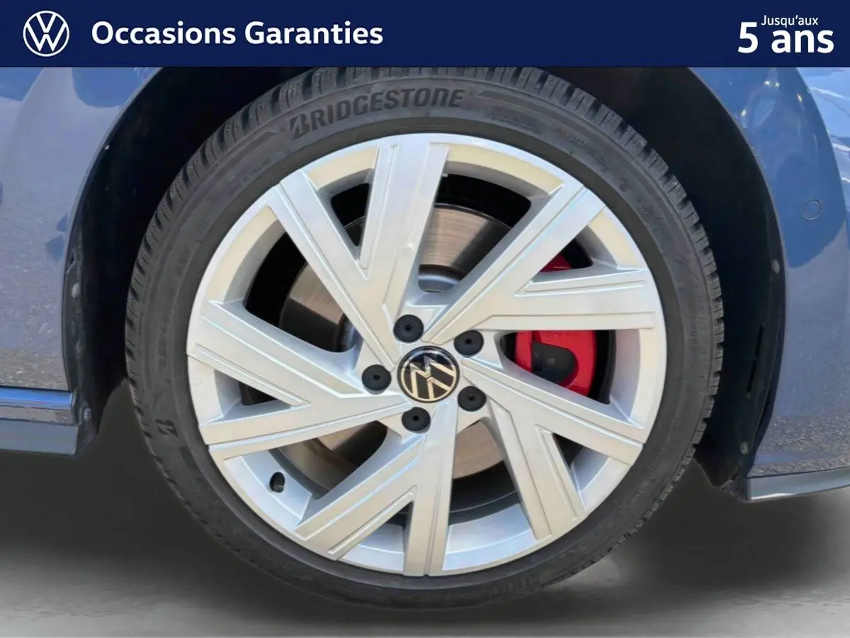 Gros plan sur la roue avant gauche d'une Volkswagen Golf 1.5 eHybrid bleue avec jante alliage 17'' Richmond et étrier de frein rouge.