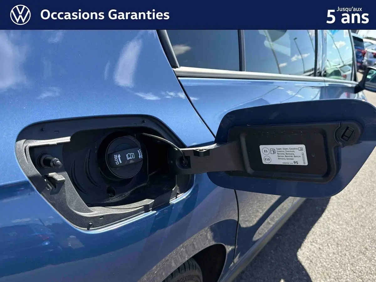 Vue rapprochée de la trappe à carburant ouverte côté gauche d'une Volkswagen Golf 1.5 eHybrid bleue 2025.