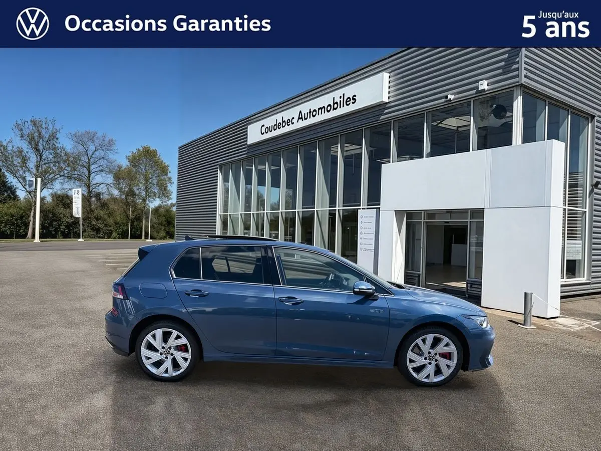Vue latérale gauche d'une Volkswagen Golf 1.5 eHybrid 272 DSG6 bleue métallisée, avec jantes alliage 17'' et badges GTE visibles.