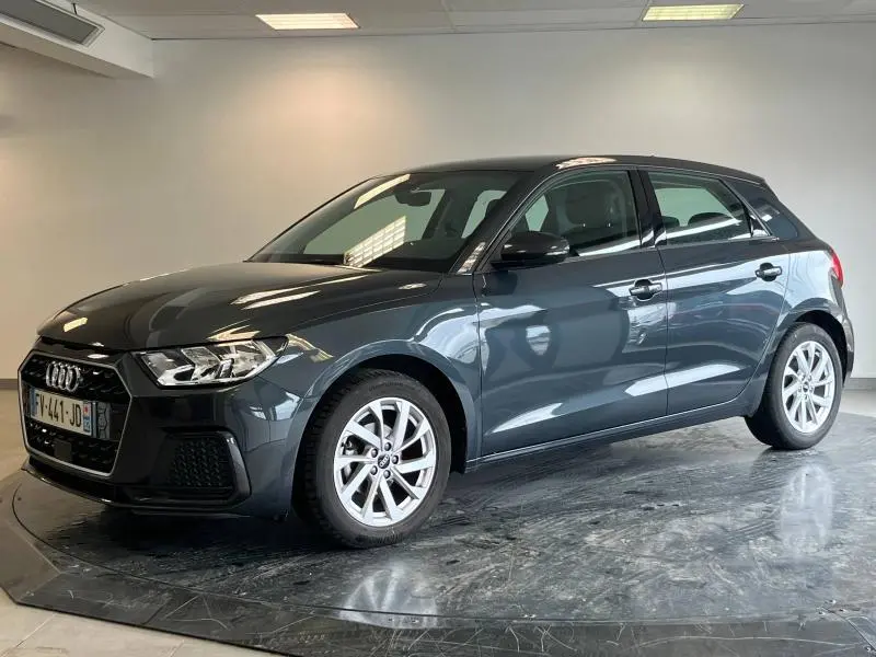 Audi A1 Sportback noir Mythic métallisé vue 3/4 avant droit en intérieur avec jantes alu et calandre noire.