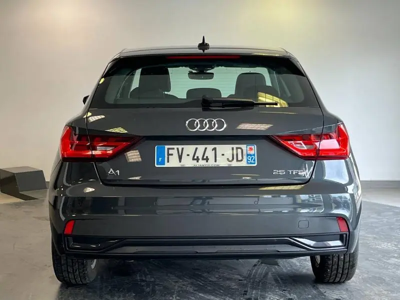 Vue arrière d'une Audi A1 Sportback 25 TFSI Business line noire Mythic métallisée dans un intérieur lumineux.