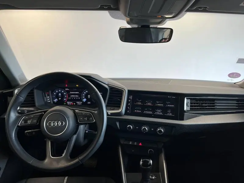 Vue intérieure frontale du tableau de bord et volant cuir noir de l'Audi A1 Sportback 2020 avec écran tactile et commandes multifonctions.