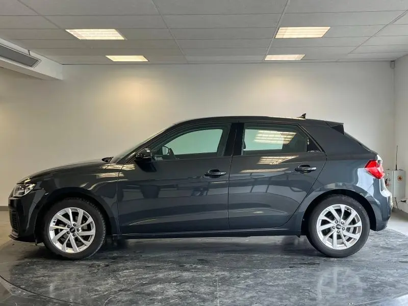 Profil latéral droit d'une Audi A1 Sportback 25 TFSI Business line noire Mythic métallisée dans un intérieur neutre.