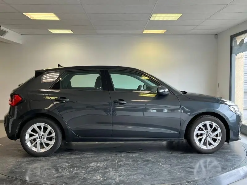 Profil droit d'une Audi A1 Sportback 2020 noir Mythic métallisé avec jantes alu en intérieur showroom.