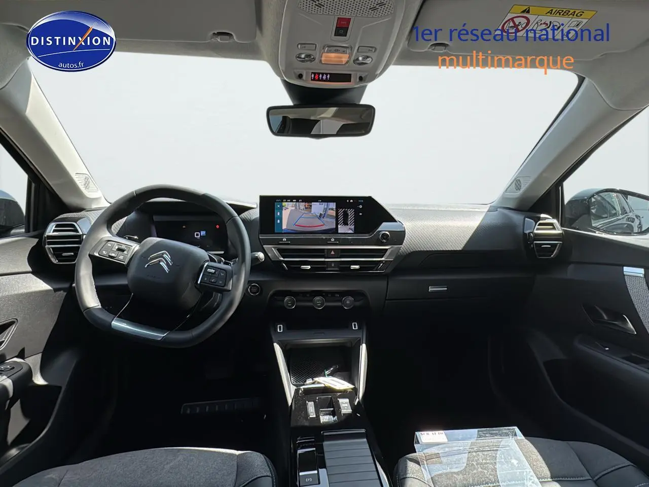 Intérieur de la Citroën C4 2025 vu de face, tableau de bord noir avec écran tactile et volant cuir.