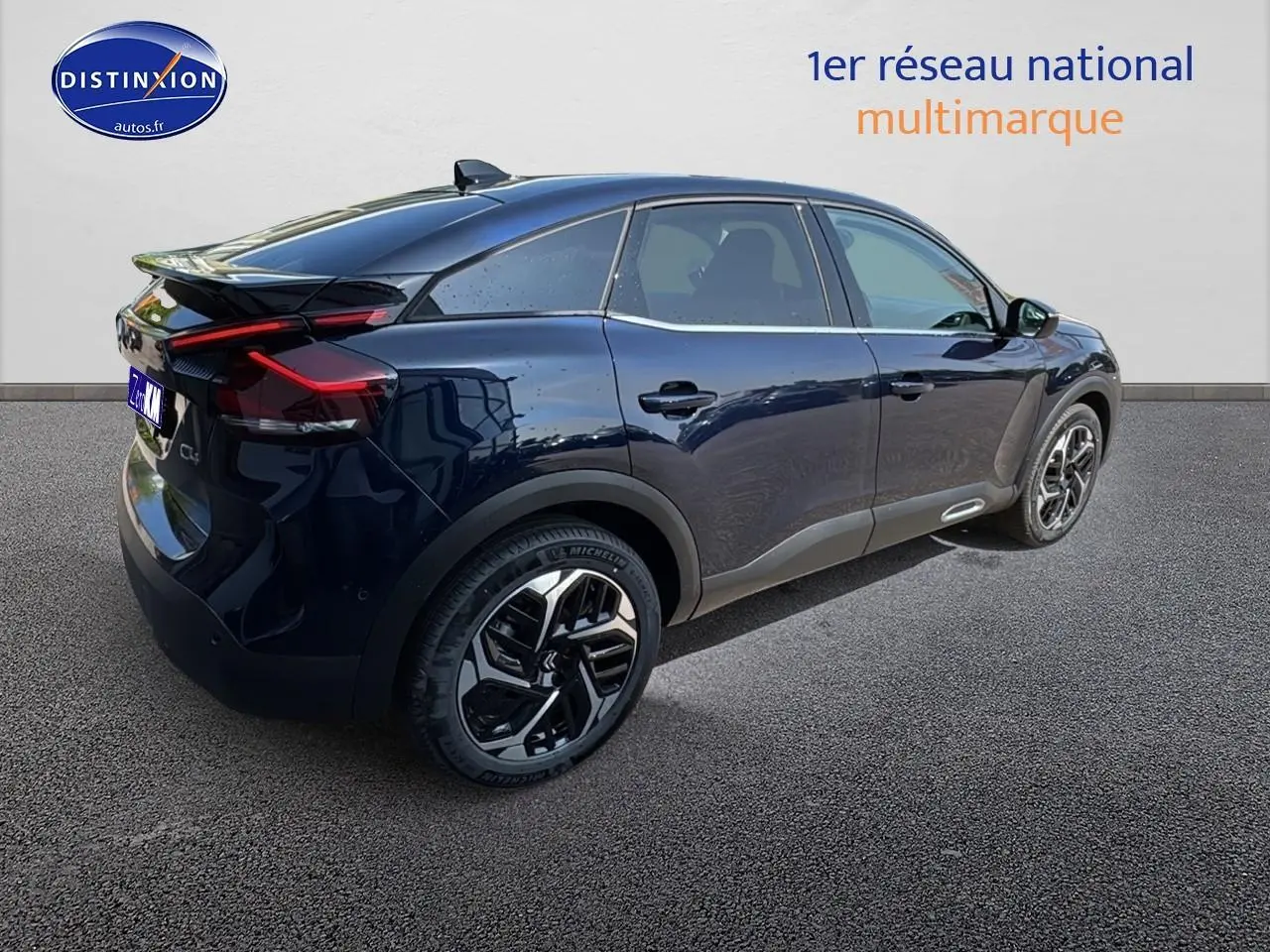 Vue 3/4 arrière droite d'une Citroën C4 bleu eclipse avec jantes alu et vitres surteintées sur fond neutre.