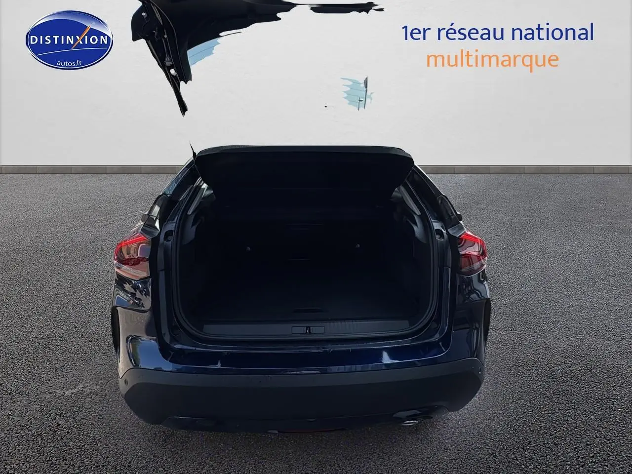 Vue arrière d'une Citroën C4 bleu eclipse avec coffre ouvert sur sol gris.