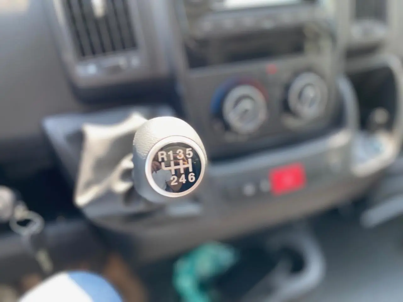 Le levier de vitesses manuel du Citroën Jumper 2023 en gros plan, avec le tableau de bord flou en arrière-plan.