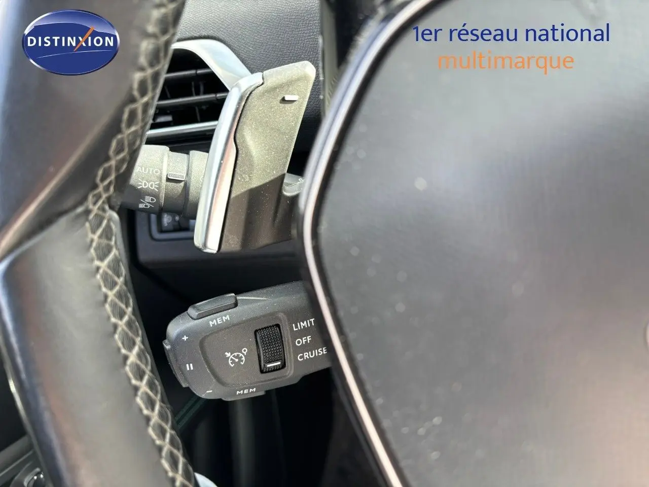 Gros plan sur la commande de régulateur de vitesse derrière le volant d'un Peugeot 3008 gris platinium.