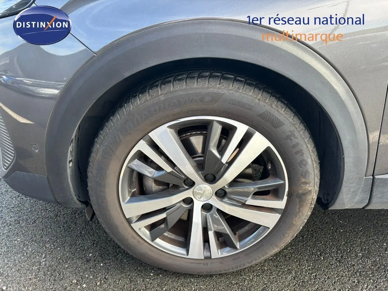 Gros plan sur la roue avant gauche du Peugeot 3008 gris platinium, mettant en valeur la jante alliage et le pneu Firestone.