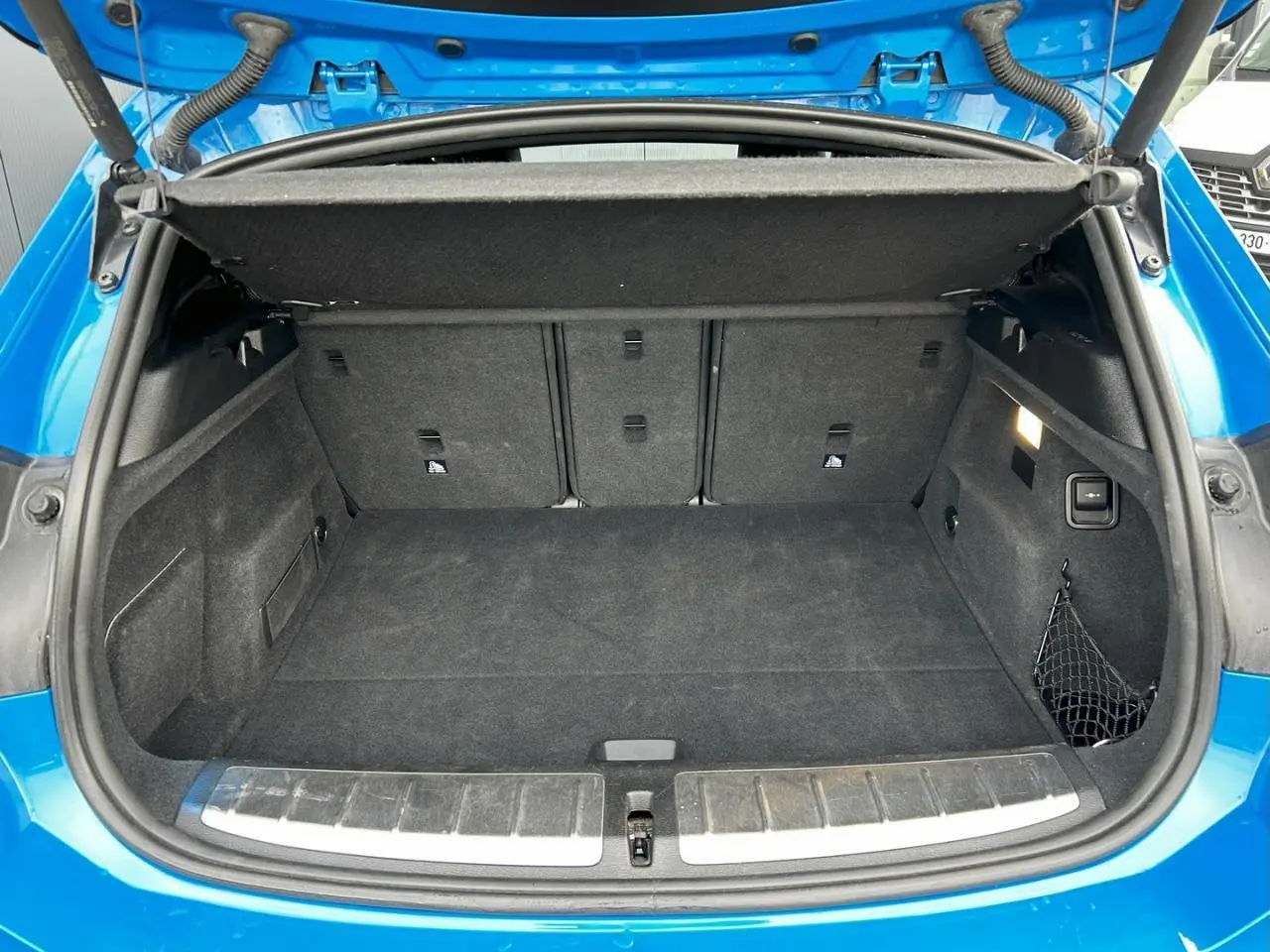 Coffre ouvert vu de l'arrière du BMW X2 bleu Misano, montrant un espace de rangement propre et bien agencé.