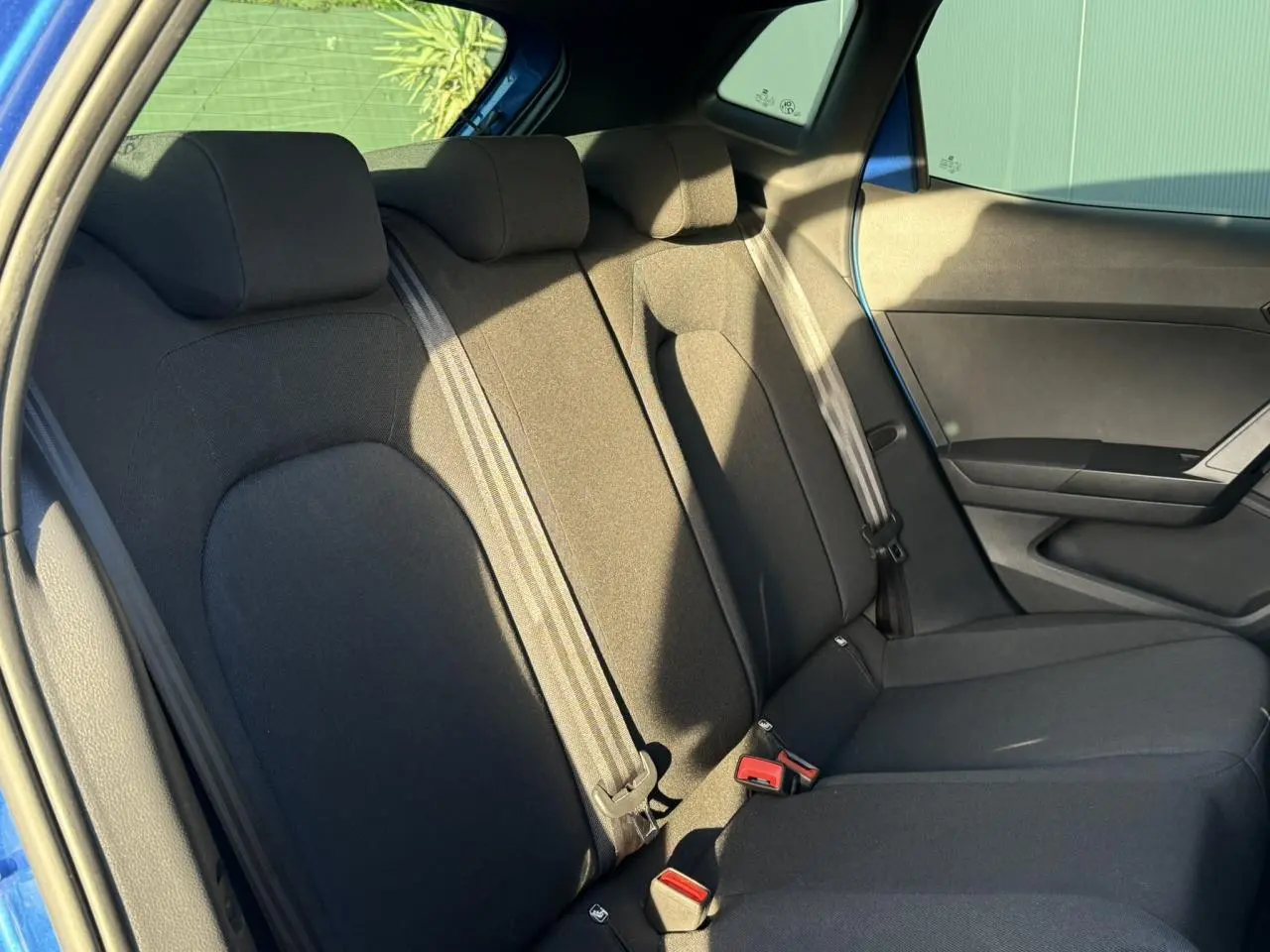 Vue intérieure sur la banquette arrière noire du SEAT IBIZA bleu saphir, avec ceintures et appuie-têtes visibles.
