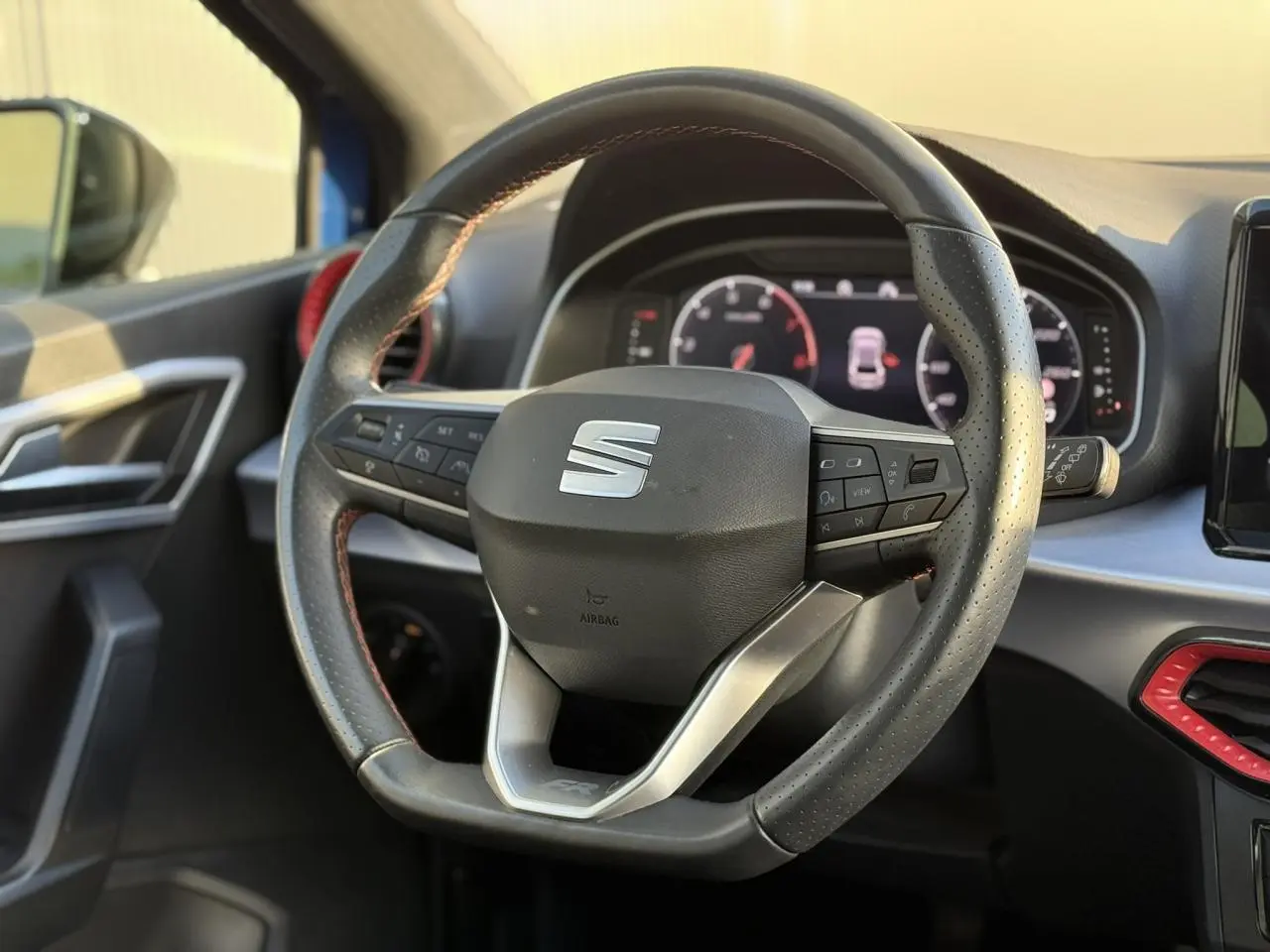 Volant multifonction de la SEAT Ibiza TSI 115 FR 2025, vue rapprochée de l'intérieur côté conducteur avec détails rouges.