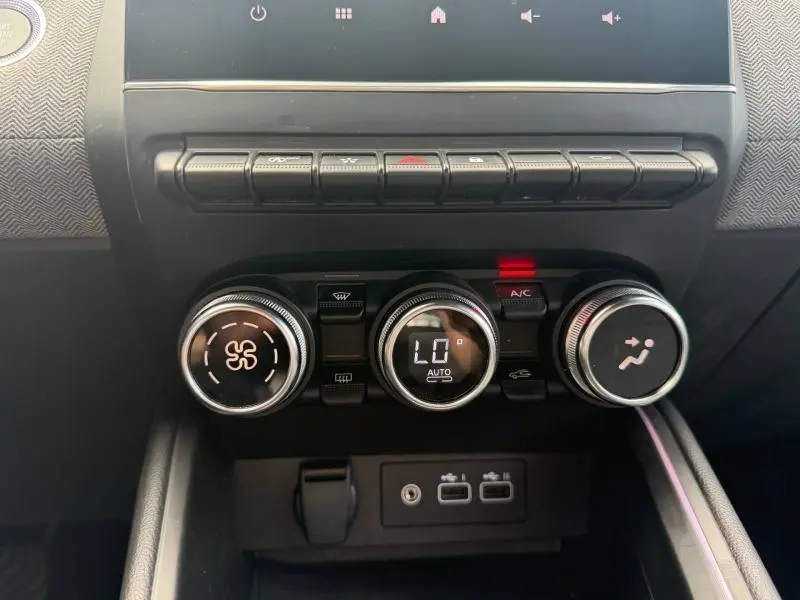 Gros plan sur la console centrale de la Renault Clio gris schiste, montrant les commandes de climatisation et les ports USB.