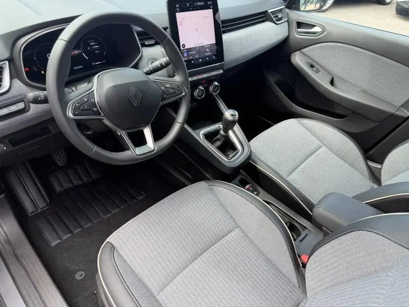 Intérieur avant droit de Renault Clio gris Schiste 2025 avec volant multifonction et boîte manuelle visible.