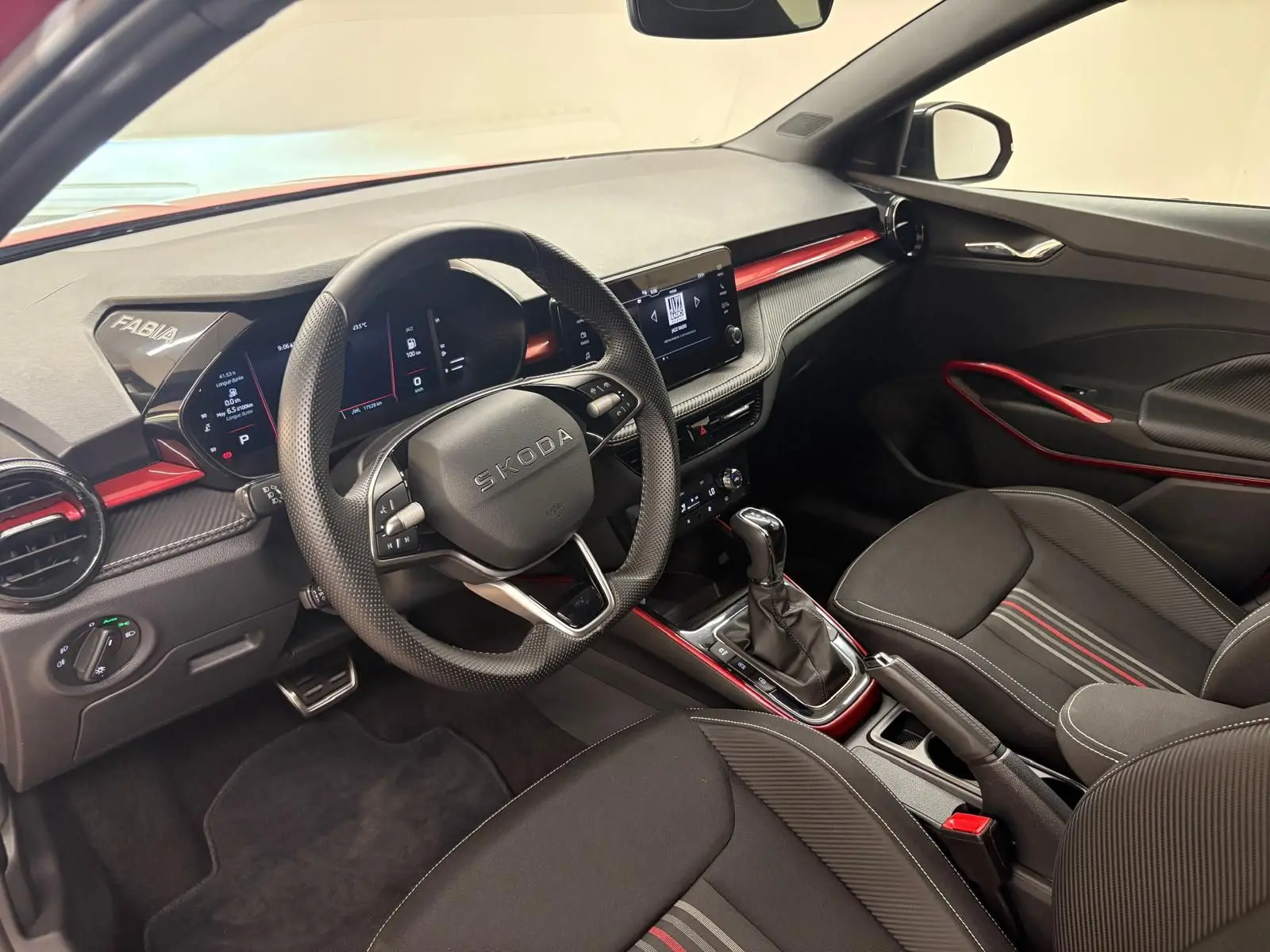 Vue intérieure côté conducteur de la Skoda Fabia Monte Carlo 2025, avec finitions rouges et volant multifonction.