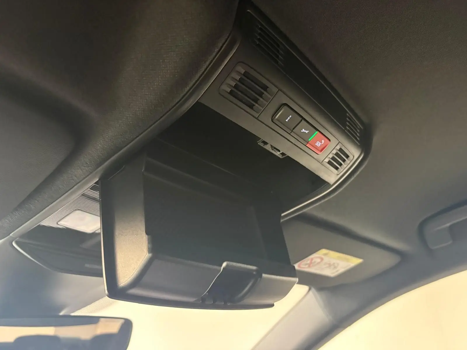 Gros plan sur le rangement plafond ouvert avec commandes d'assistance dans l'habitacle noir du Skoda Fabia 2025.