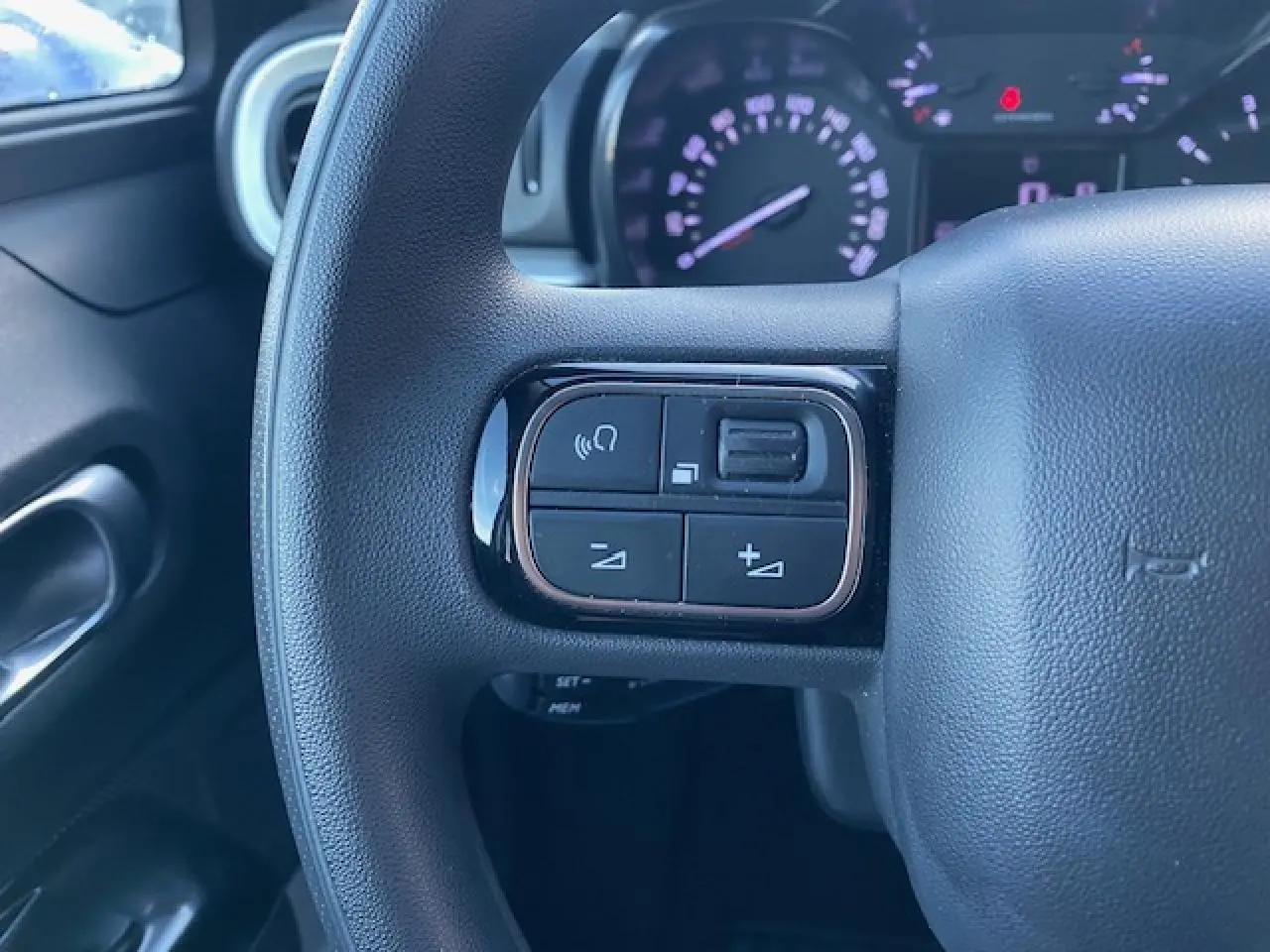 Gros plan sur le volant côté gauche de la Citroën C3 Shine 2023, montrant les commandes audio intégrées.