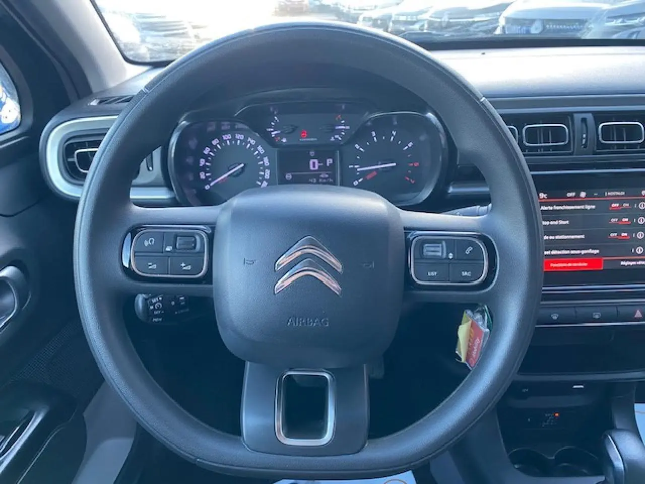 Vue rapprochée du volant et du tableau de bord d'une Citroën C3 Shine 2023 avec commandes intégrées et écran tactile.