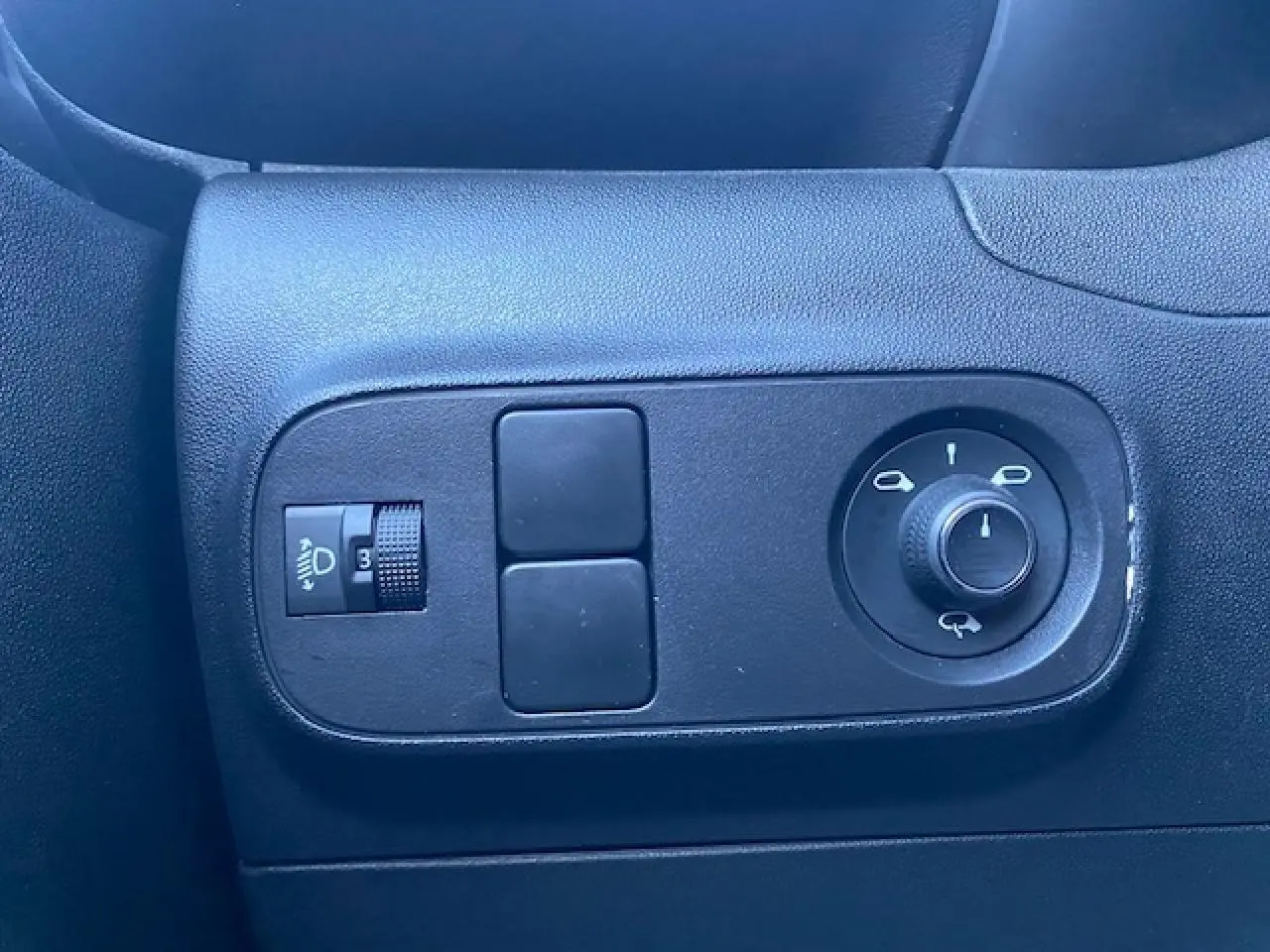 Vue rapprochée des commandes de réglage des rétroviseurs et des phares sur la porte côté gauche d'une Citroën C3 Shine noire toit rouge.