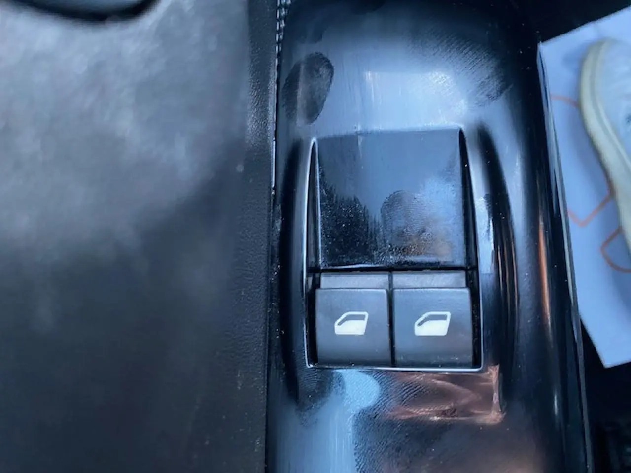 Gros plan sur les boutons de commande des vitres électriques côté conducteur d'une Citroën C3 Shine 2023 noir toit rouge.