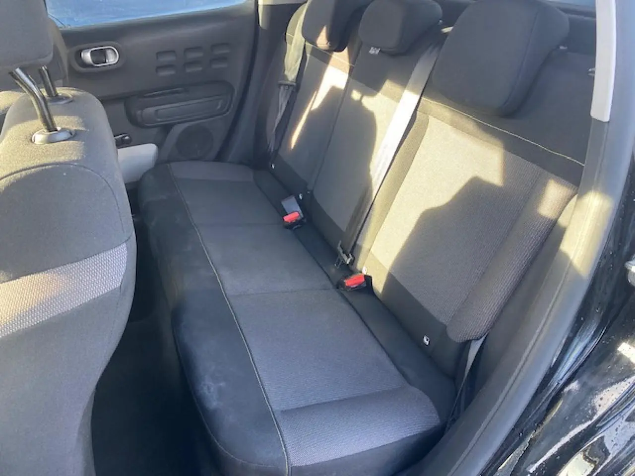 Banquette arrière noire vue côté droit de la Citroën C3 Shine 2023 avec portes ouvertes et ceintures visibles.