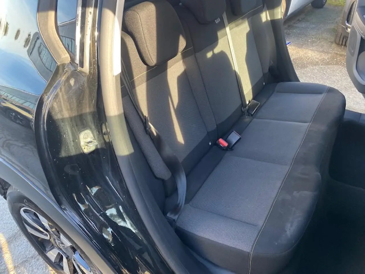 Vue côté gauche sur l'arrière d'une Citroën C3 2023 noire toit rouge, montrant la banquette arrière en tissu gris foncé.