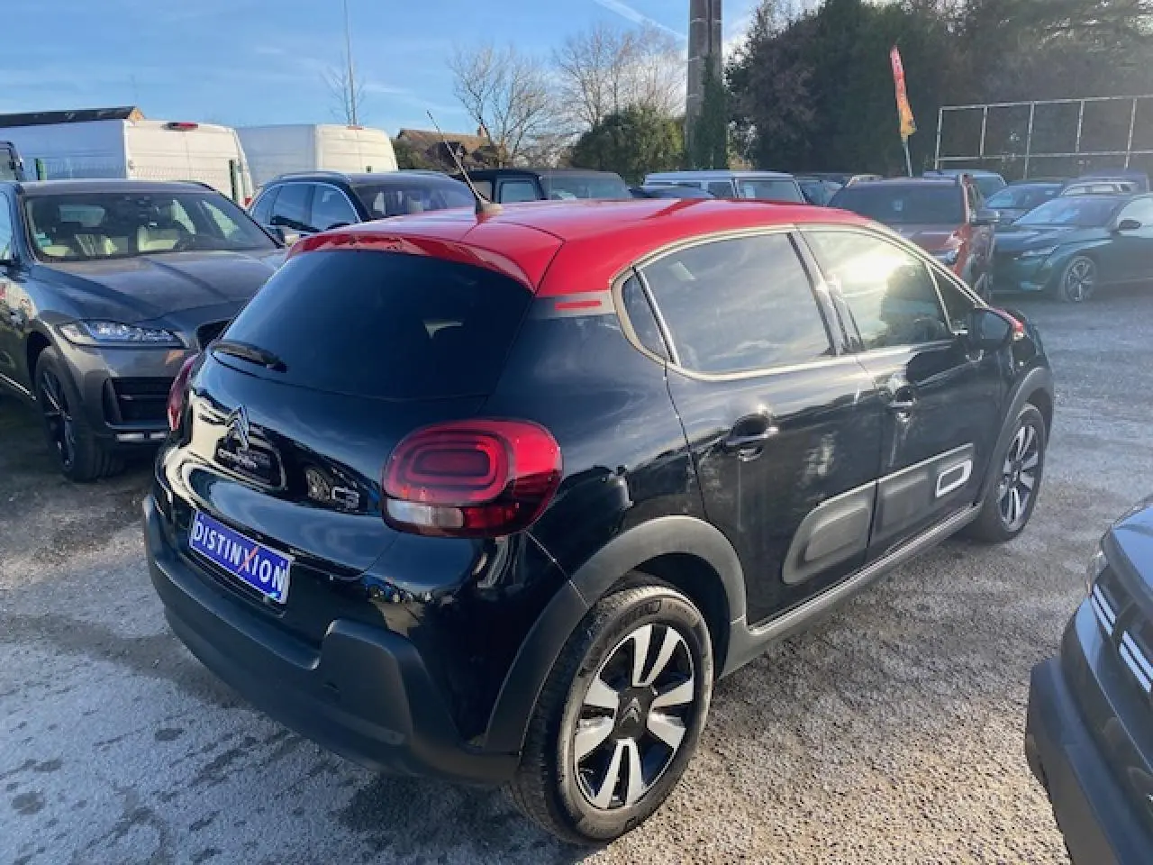 Citroën C3 Shine 2023 noir avec toit rouge, vue 3/4 arrière droit, jantes alliage et Airbump latéraux visibles.