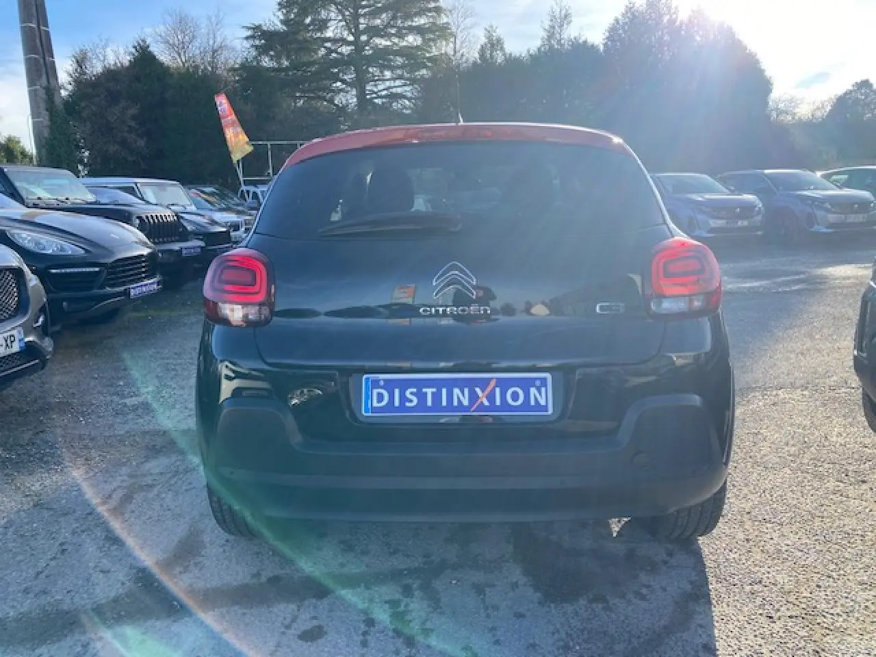 Vue arrière d'une Citroën C3 noire avec toit rouge, feux arrière LED et plaque d'immatriculation Distinxion.