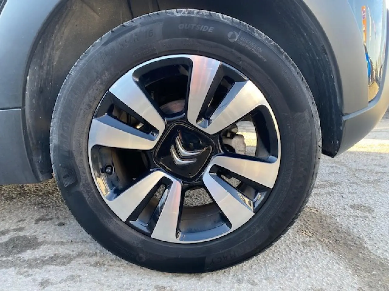 Gros plan sur la jante alliage diamantée 16 pouces noire et argentée d'une Citroën C3 Shine 2023 toit rouge.