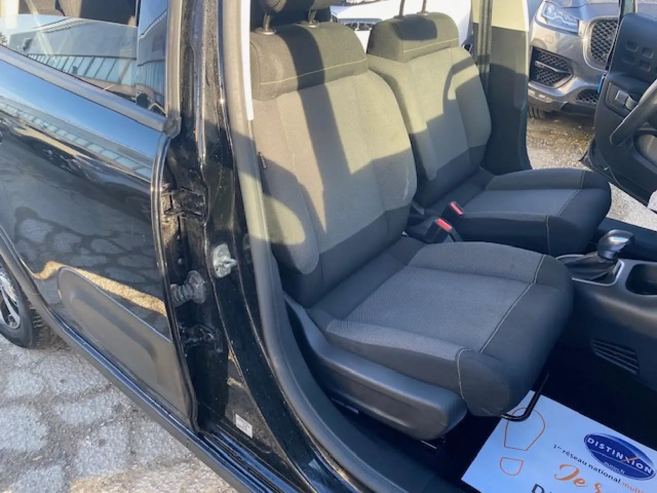 Vue intérieure côté gauche des sièges avant noirs d'une Citroën C3 Shine 2023 avec porte ouverte.