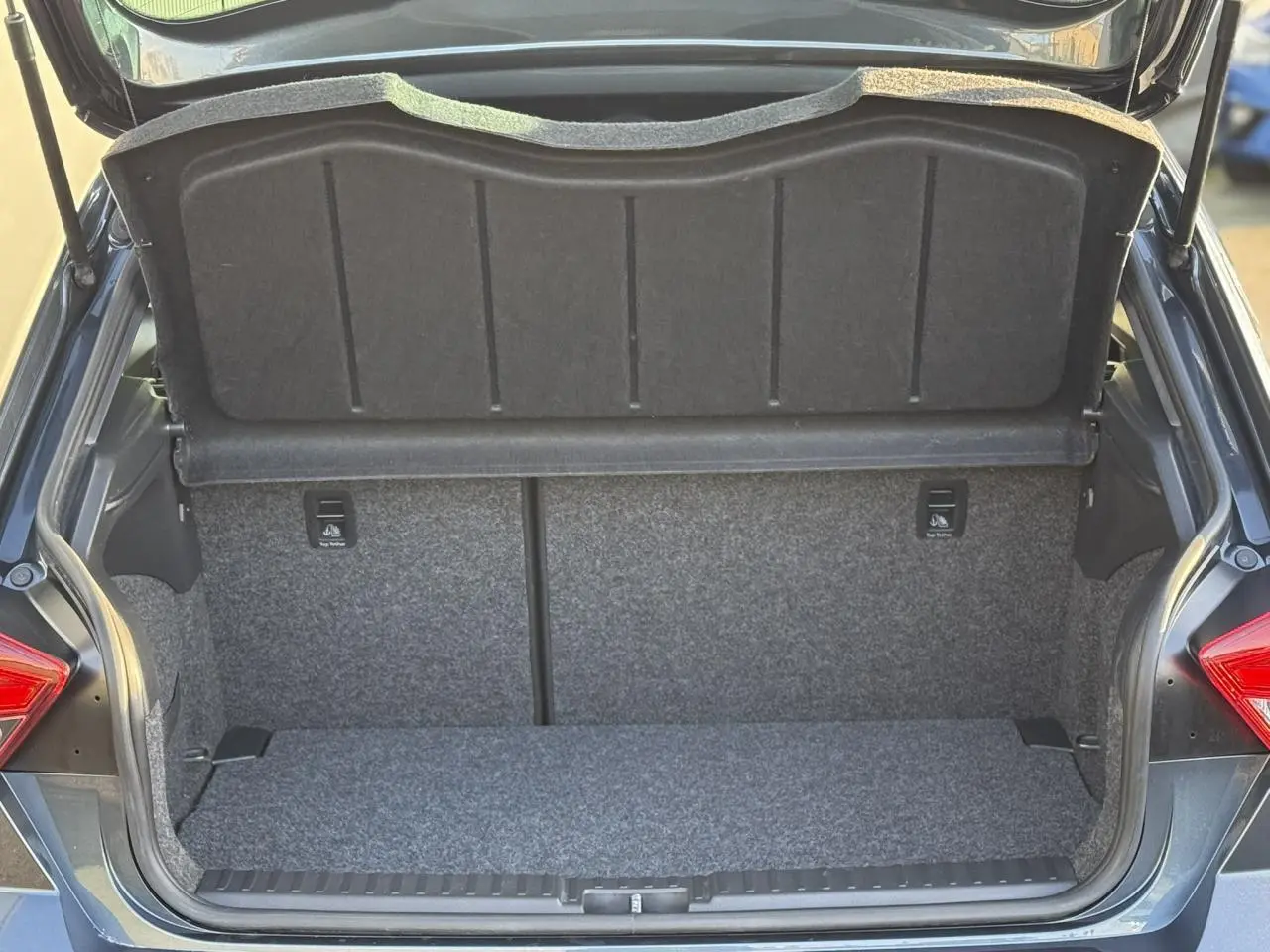 Coffre ouvert vu de l'arrière d'une SEAT IBIZA gris magnétique avec intérieur de coffre en tissu gris.